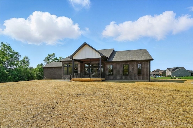 8559 Wandering Brook Way, Waynesville, OH 45068 - rear view of house featuring a sunroom, a lawn, brick siding, and board and batten siding
