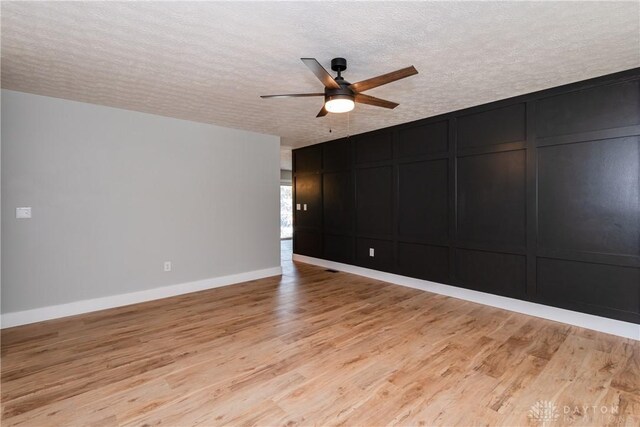 390 Washington Ave, Wilmington, OH 45177 - spare room featuring a textured ceiling, a ceiling fan, a decorative wall, and light wood finished floors