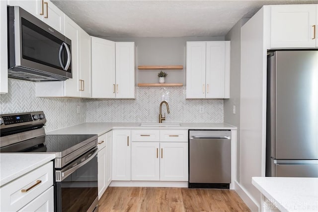 390 Washington Ave, Wilmington, OH 45177 - kitchen with stainless steel appliances, open shelves, white cabinetry, and light wood finished floors