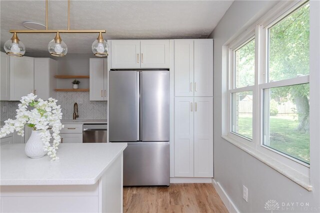 390 Washington Ave, Wilmington, OH 45177 - kitchen featuring stainless steel appliances, open shelves, decorative backsplash, light countertops, and light wood finished floors