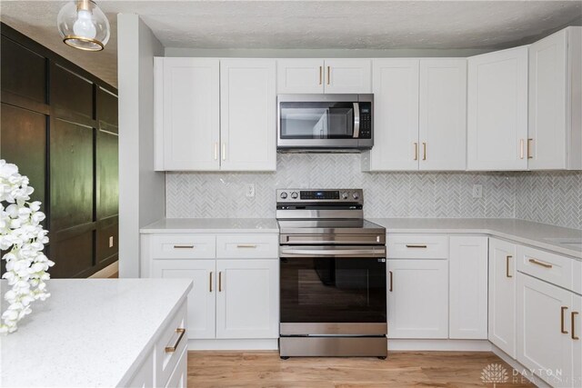 390 Washington Ave, Wilmington, OH 45177 - kitchen with appliances with stainless steel finishes, light wood-style floors, light countertops, and white cabinetry