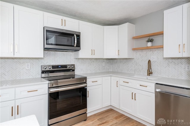 390 Washington Ave, Wilmington, OH 45177 - kitchen featuring stainless steel appliances, open shelves, light countertops, white cabinetry, and light wood-type flooring