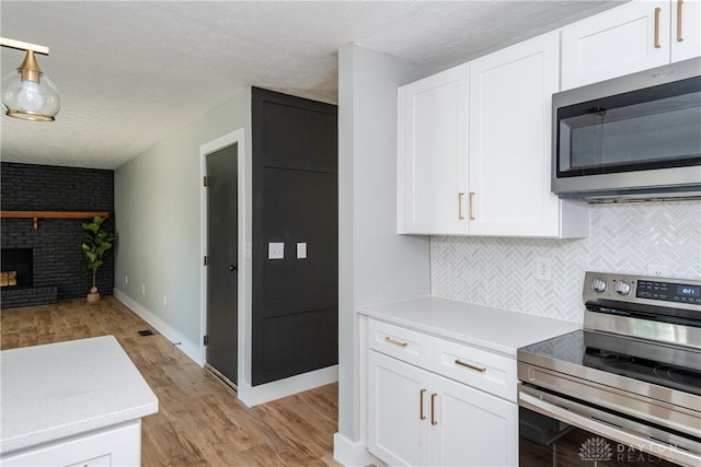 390 Washington Ave, Wilmington, OH 45177 - kitchen featuring stainless steel appliances, light wood-style flooring, light countertops, white cabinets, and backsplash