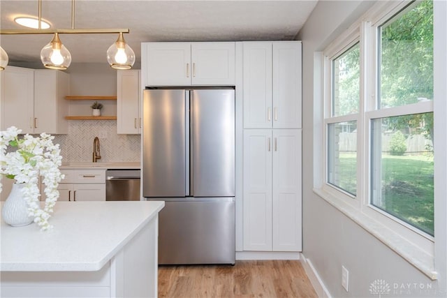 390 Washington Ave, Wilmington, OH 45177 - kitchen with appliances with stainless steel finishes, open shelves, light countertops, light wood finished floors, and decorative backsplash