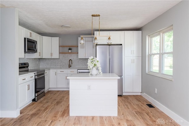 390 Washington Ave, Wilmington, OH 45177 - kitchen with stainless steel appliances, open shelves, light countertops, light wood finished floors, and tasteful backsplash