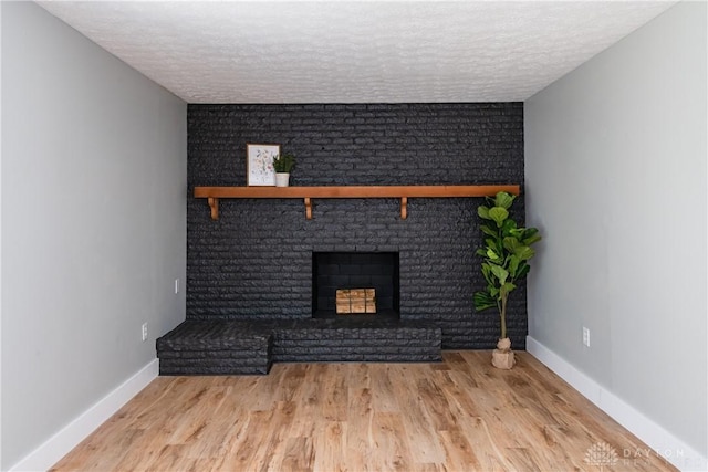 390 Washington Ave, Wilmington, OH 45177 - unfurnished living room with a textured ceiling, wood finished floors, and a brick fireplace