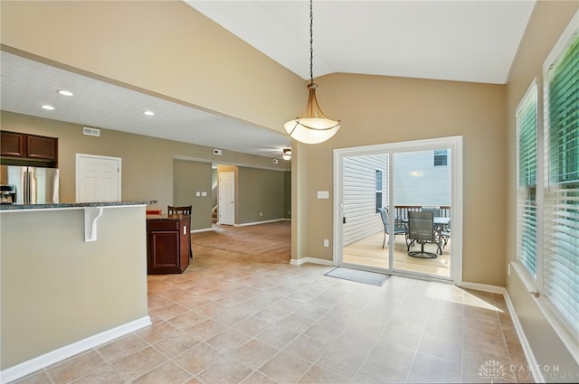 1956 Daffodil Dr, Xenia, OH 45385 - kitchen with freestanding refrigerator, light tile patterned flooring, dark stone countertops, hanging light fixtures, and lofted ceiling