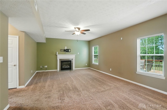 1956 Daffodil Dr, Xenia, OH 45385 - unfurnished living room featuring a ceiling fan, a fireplace with flush hearth, carpet flooring, and a textured ceiling