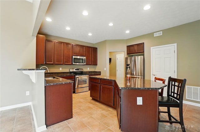1956 Daffodil Dr, Xenia, OH 45385 - kitchen featuring stainless steel appliances, a kitchen bar, a center island, dark stone counters, and recessed lighting