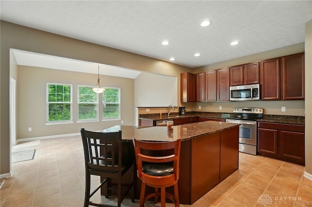 1956 Daffodil Dr, Xenia, OH 45385 - kitchen featuring stainless steel appliances, recessed lighting, dark stone countertops, a kitchen breakfast bar, and a kitchen island
