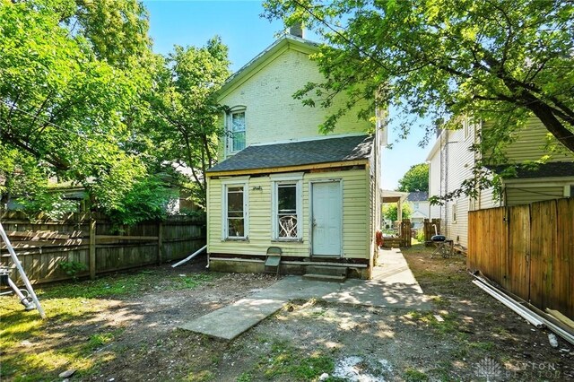 57 S Torrence St, Dayton, OH 45403 - back of property with entry steps, a chimney, a fenced backyard, and roof with shingles