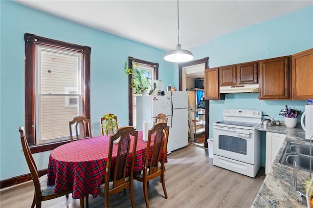 57 S Torrence St, Dayton, OH 45403 - kitchen with white appliances, under cabinet range hood, light wood finished floors, brown cabinets, and hanging light fixtures