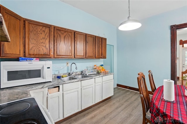 57 S Torrence St, Dayton, OH 45403 - kitchen featuring white microwave, light wood-style floors, hanging light fixtures, brown cabinetry, and light countertops