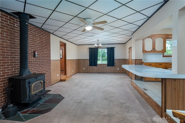 3372 Home Acres Ave, Beavercreek, OH 45431 - unfurnished living room with a wainscoted wall, a wood stove, light carpet, wooden walls, and ceiling fan