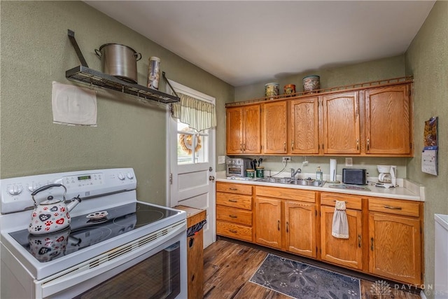 2151 Newgate Ave, Dayton, OH 45420 - kitchen with white range with electric stovetop, dark wood finished floors, light countertops, brown cabinetry, and a textured wall