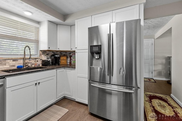 6814 Rushleigh Rd, Englewood, OH 45322 - kitchen featuring stainless steel appliances, white cabinetry, wood finished floors, a textured ceiling, and tasteful backsplash