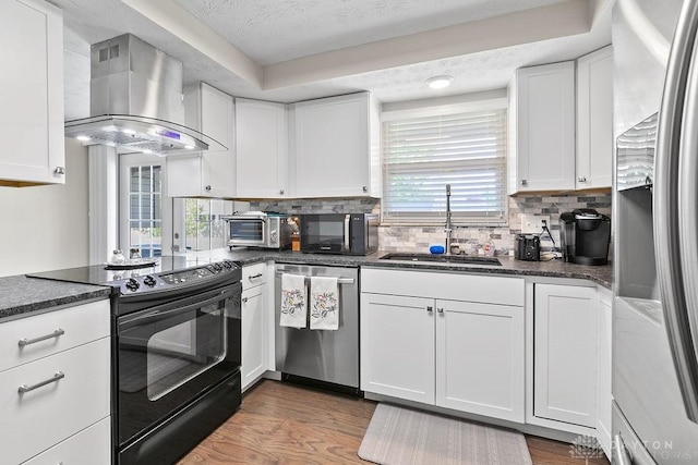 6814 Rushleigh Rd, Englewood, OH 45322 - kitchen featuring black appliances, wall chimney exhaust hood, healthy amount of natural light, white cabinetry, and a textured ceiling