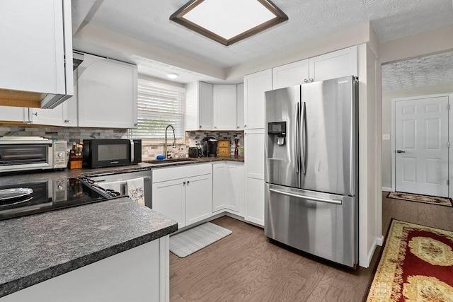 6814 Rushleigh Rd, Englewood, OH 45322 - kitchen featuring stainless steel refrigerator with ice dispenser, black microwave, wood finished floors, white cabinetry, and decorative backsplash