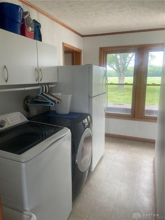 311 Swailes Rd, Troy, OH 45373 - laundry area featuring crown molding, independent washer and dryer, cabinet space, a textured ceiling, and light tile patterned flooring