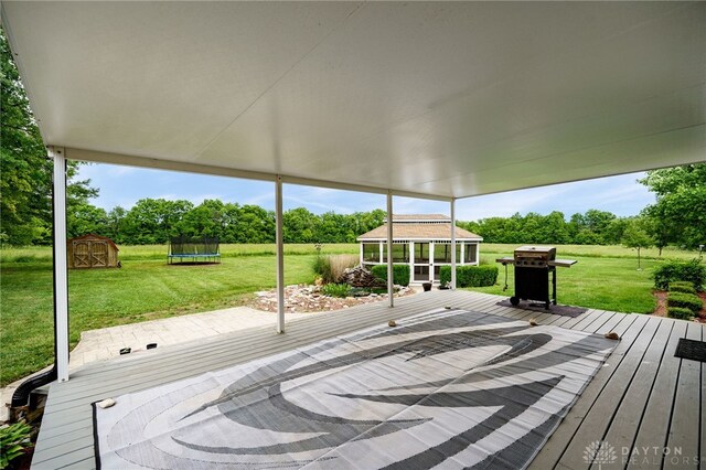 8282 Hile Ln, Germantown, OH 45327 - deck with a trampoline, a grill, a lawn, and view of wooded area