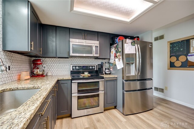 8282 Hile Ln, Germantown, OH 45327 - kitchen featuring stainless steel appliances, backsplash, light wood-type flooring, and light stone counters