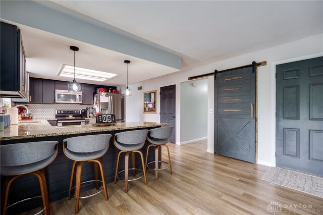 8282 Hile Ln, Germantown, OH 45327 - kitchen featuring stainless steel appliances, a barn door, light stone countertops, a peninsula, and decorative backsplash