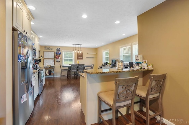 855 Quarry Rd, Silver Creek Twp, OH 45335 - kitchen featuring appliances with stainless steel finishes, cream cabinetry, a peninsula, a kitchen breakfast bar, and dark wood-type flooring