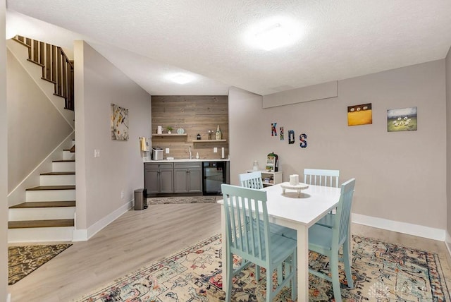 1015 Settlemyre Rd, Oregonia, OH 45054 - dining room featuring stairs, beverage cooler, light wood finished floors, bar area, and a textured ceiling