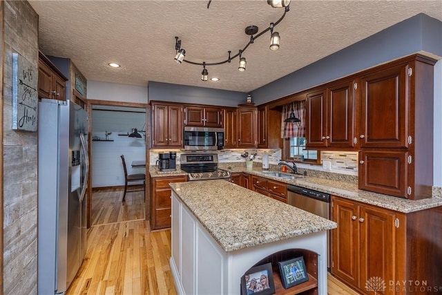 2025 Seneca Dr, Troy, OH 45373 - kitchen featuring stainless steel appliances, light wood-style floors, a kitchen island, light stone counters, and a textured ceiling