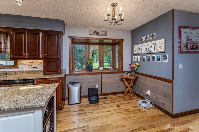 2025 Seneca Dr, Troy, OH 45373 - kitchen with light wood-type flooring, a chandelier, light stone counters, a textured ceiling, and stainless steel dishwasher