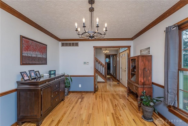2025 Seneca Dr, Troy, OH 45373 - corridor featuring a chandelier, light wood-type flooring, a textured ceiling, stairs, and crown molding