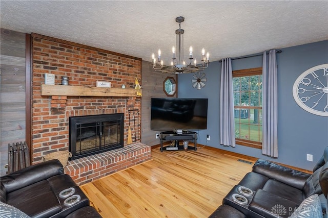2025 Seneca Dr, Troy, OH 45373 - living area featuring wood finished floors, a chandelier, a textured ceiling, and a brick fireplace