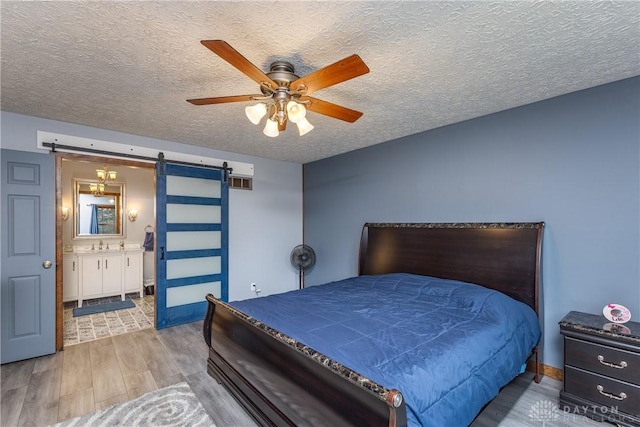 2025 Seneca Dr, Troy, OH 45373 - bedroom featuring a barn door, wood finished floors, a textured ceiling, ensuite bathroom, and a ceiling fan