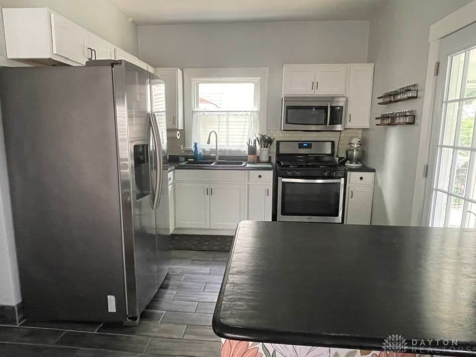 226 Sherman Ave, Hamilton, OH 45013 - kitchen featuring appliances with stainless steel finishes, dark countertops, white cabinets, and wood tiled floors
