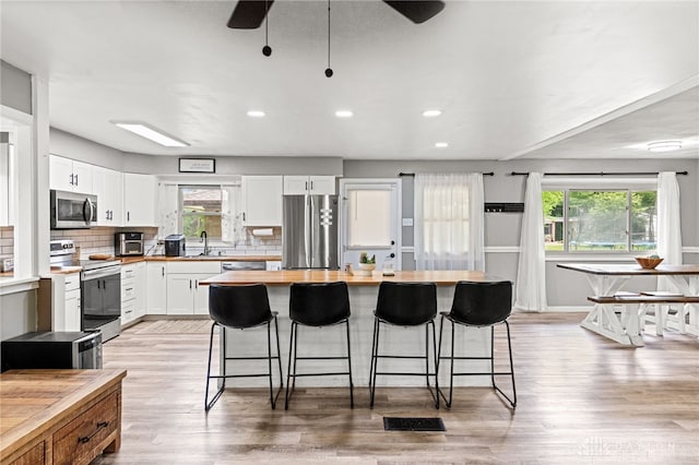 8684 Woodview Dr, Cincinnati, OH 45231 - kitchen with appliances with stainless steel finishes, butcher block countertops, plenty of natural light, a kitchen breakfast bar, and recessed lighting