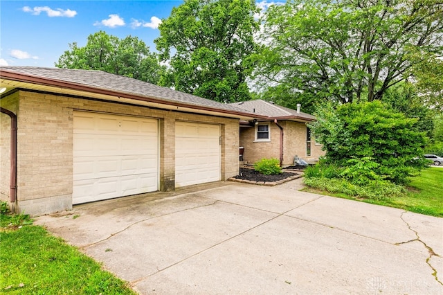 8684 Woodview Dr, Cincinnati, OH 45231 - view of side of property with driveway, brick siding, a garage, and a shingled roof