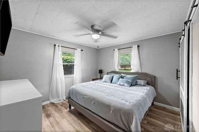 8684 Woodview Dr, Cincinnati, OH 45231 - bedroom with a barn door, multiple windows, and light wood-type flooring