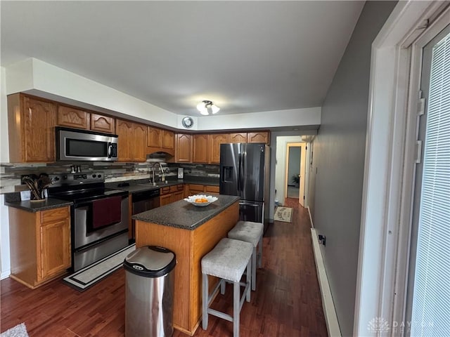 1637 Lammes Ln, New Carlisle, OH 45344 - kitchen featuring stainless steel appliances, decorative backsplash, dark countertops, and a kitchen bar