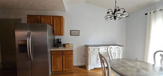 919 N Cherry St, Eaton, OH 45320 - kitchen with stainless steel fridge with ice dispenser, brown cabinets, a chandelier, light wood-style flooring, and vaulted ceiling