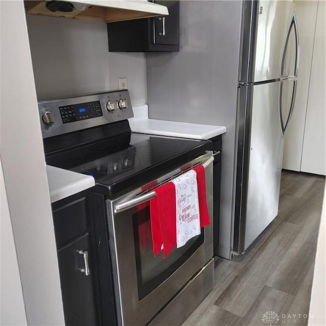 1116 Eagle Feather Cir Unit B, West Carrollton, OH 45449 - kitchen featuring appliances with stainless steel finishes, under cabinet range hood, wood finished floors, light countertops, and dark cabinets