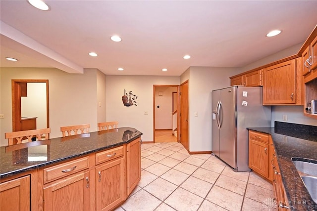 1241 Wind Field Ct, Washington Twp, OH 45458 - kitchen featuring stainless steel fridge with ice dispenser, recessed lighting, light tile patterned flooring, dark stone counters, and brown cabinets