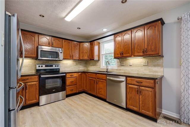 1360 Adamsmoor Dr, Waynesville, OH 45068 - kitchen featuring appliances with stainless steel finishes, light wood-style flooring, brown cabinets, backsplash, and recessed lighting
