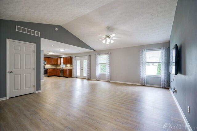 1360 Adamsmoor Dr, Waynesville, OH 45068 - unfurnished living room featuring vaulted ceiling, light wood finished floors, a ceiling fan, a textured ceiling, and plenty of natural light
