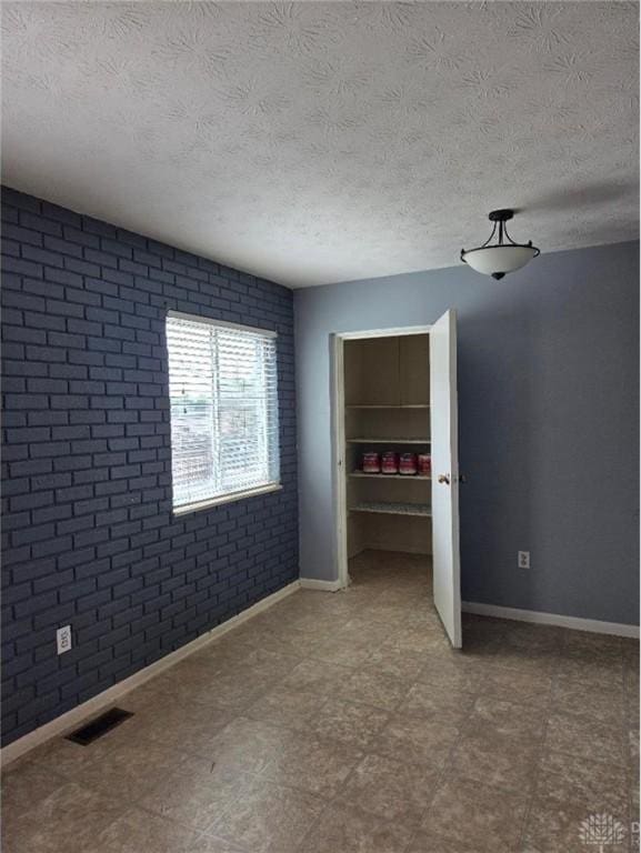5660 Coach Dr Unit C, Dayton, OH 45440 - unfurnished bedroom featuring brick wall and a textured ceiling