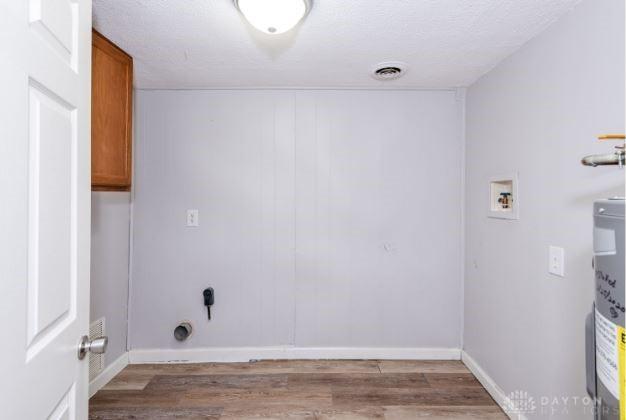 7293 Ellenridge Dr, Franklin, OH 45005 - laundry area with cabinet space, wood finished floors, hookup for a washing machine, and water heater