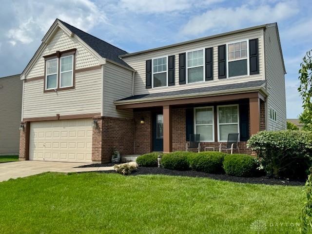 6460 Woodcreek Dr, Middletown, OH 45042 - view of front of home featuring a porch, brick siding, concrete driveway, a front yard, and an attached garage