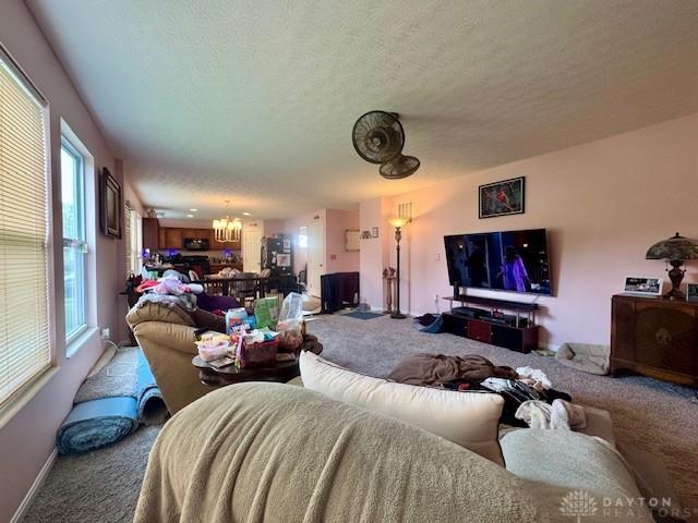 6460 Woodcreek Dr, Middletown, OH 45042 - carpeted living room with a chandelier, plenty of natural light, and a textured ceiling