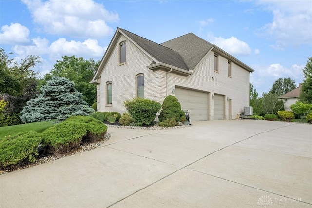 337 Yorkshire Ln, Beavercreek Twp, OH 45385 - view of side of property with a garage, concrete driveway, brick siding, and roof with shingles