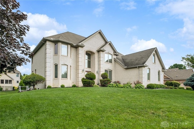 337 Yorkshire Ln, Beavercreek Twp, OH 45385 - french country inspired facade with brick siding, a front yard, and roof with shingles