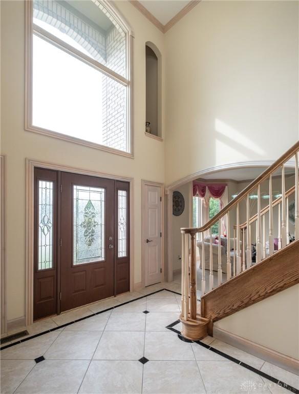 337 Yorkshire Ln, Beavercreek Twp, OH 45385 - tiled foyer with a high ceiling, arched walkways, ornamental molding, stairway, and inlaid floor details